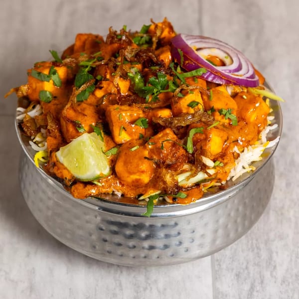 Pista House paneer biryani with red sauce, fried onions, cilantro, red onion, and lime.