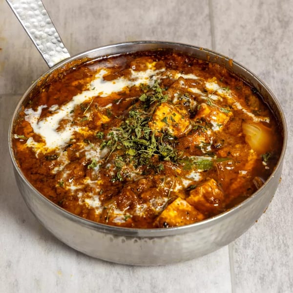 Pista House's paneer butter masala, a rich Indian curry with paneer, cream, and herbs in a metal pan.